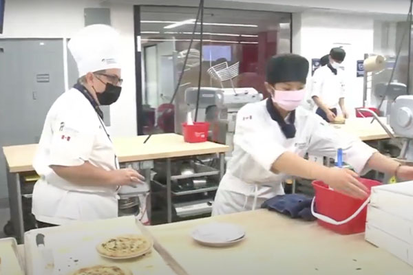 two cooks in face masks working in kitchen