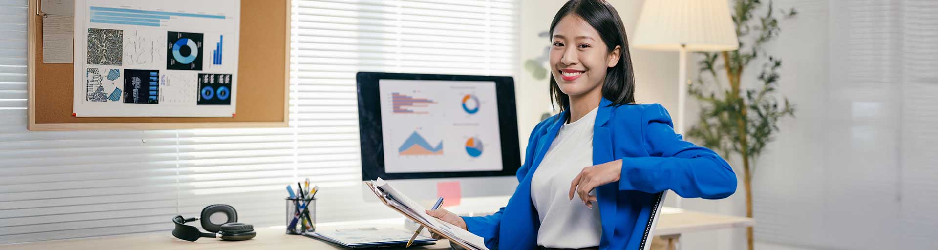 person sitting at computer smiling holding papers