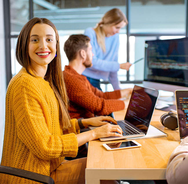 Team of a young woman as a programmer sitting in the office with people working on the background