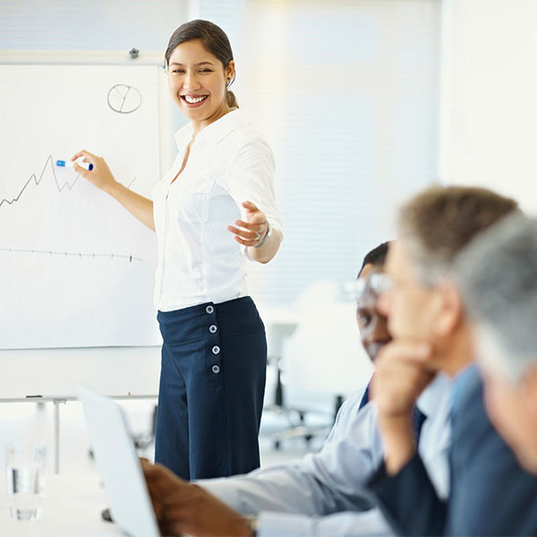 person standing at front of class pointing at board