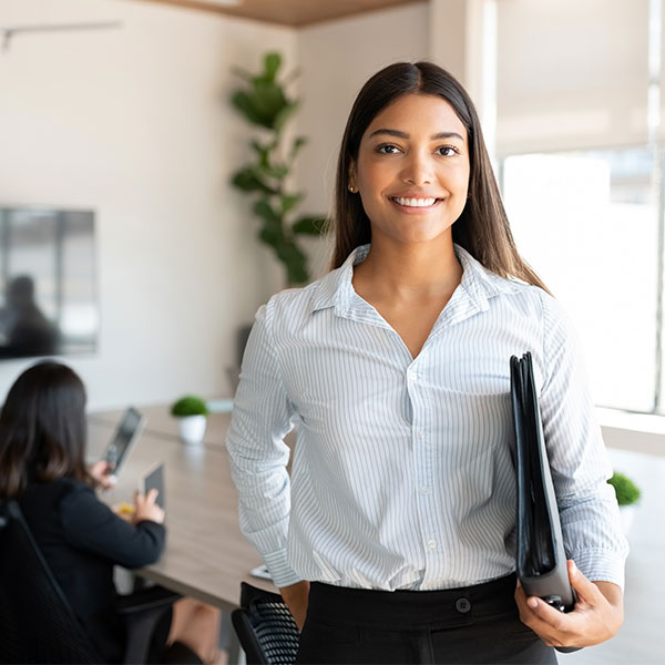 person standing smiling holding a laptop