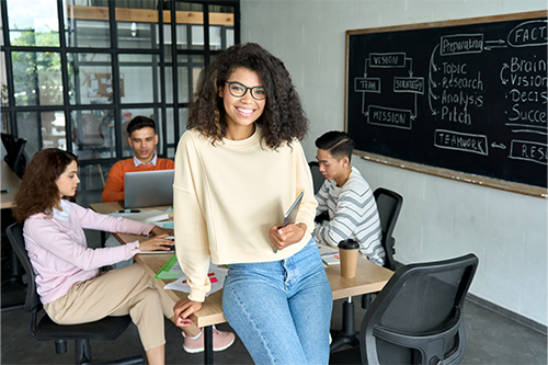 smiling student sitting on a table in a classroom