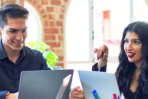 smiling people working together on a project using laptops