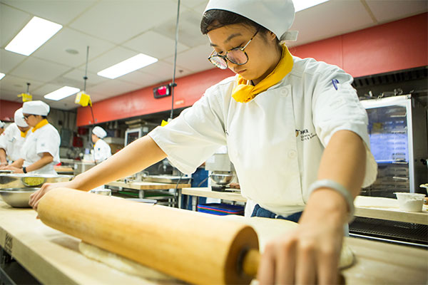 Female student rolling out dough