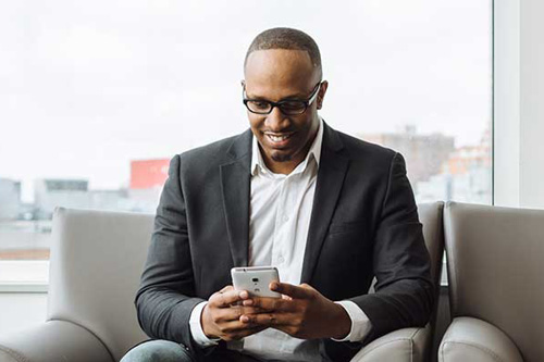 Man smiling at phone sitting on a couch