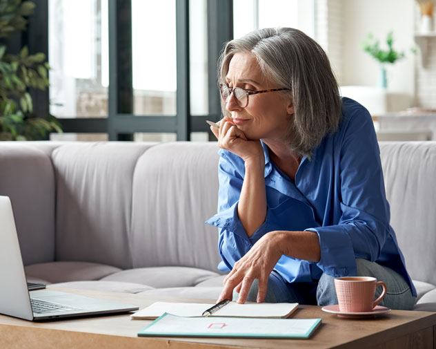 Gray-haired woman on couch looking at laptop