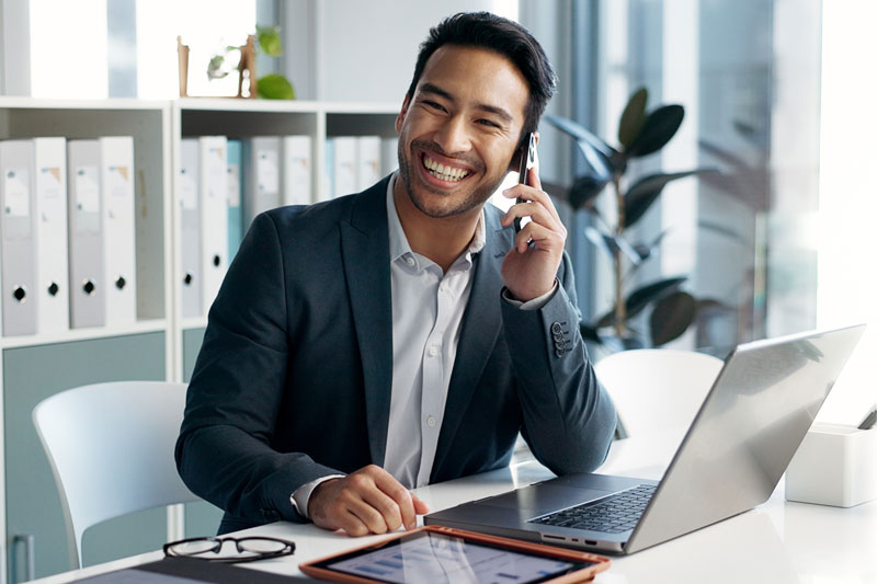 Business person smiling at desk holding cell phone