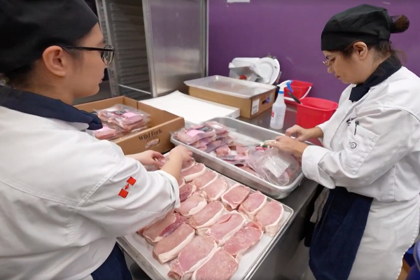 Two culinary students working with meat