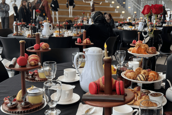 Gothic high tea table setting with various pastries, maracons, and tea cups