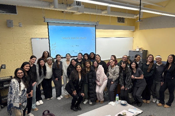 Group of students posing together in a classroom after a guest speaker presentation.