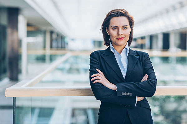 Young woman in business wear standing with armes crossed in business environment, with copy space