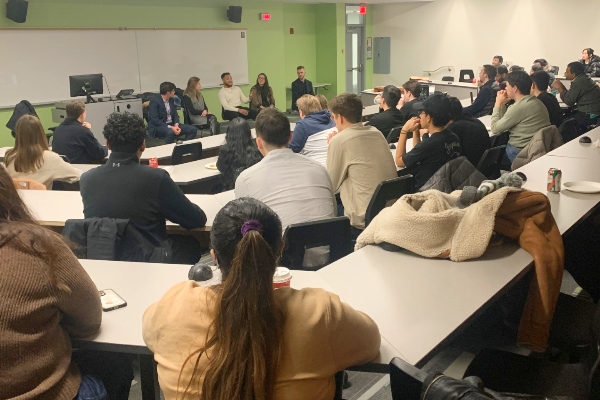 Finance students sitting at their desks in a classroom listening to the alumni panel