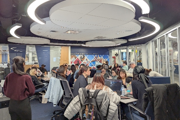 Students sitting in large groups around tables having a conversation