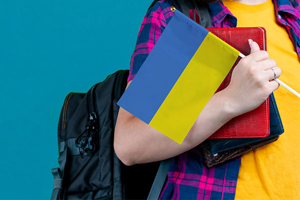 with school stuff holds in hand Ukraine flag close up