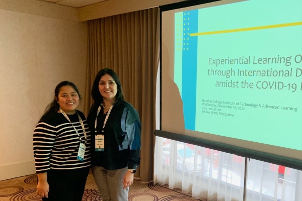 Hanadi and Clarisse standing in front of a projector at the CBIE Conference