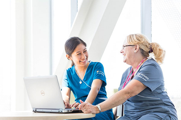Two healthcare students talking at a laptop
