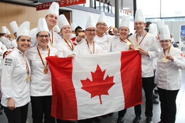 Culinary Federation (CF) Team Canada holding the Canadian flag and wearing gold medals