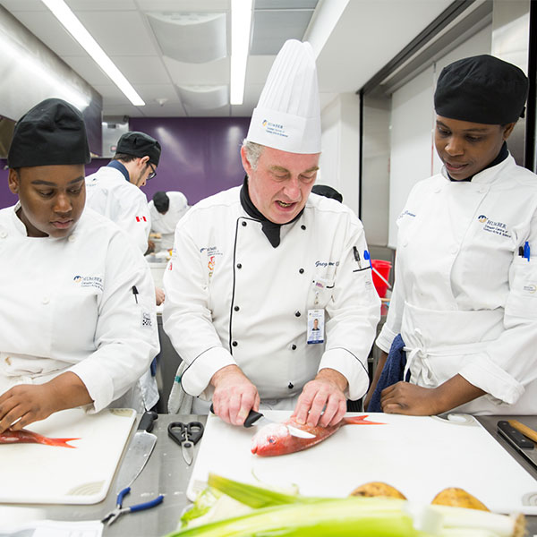 instructor demonstrating technique to culinary students