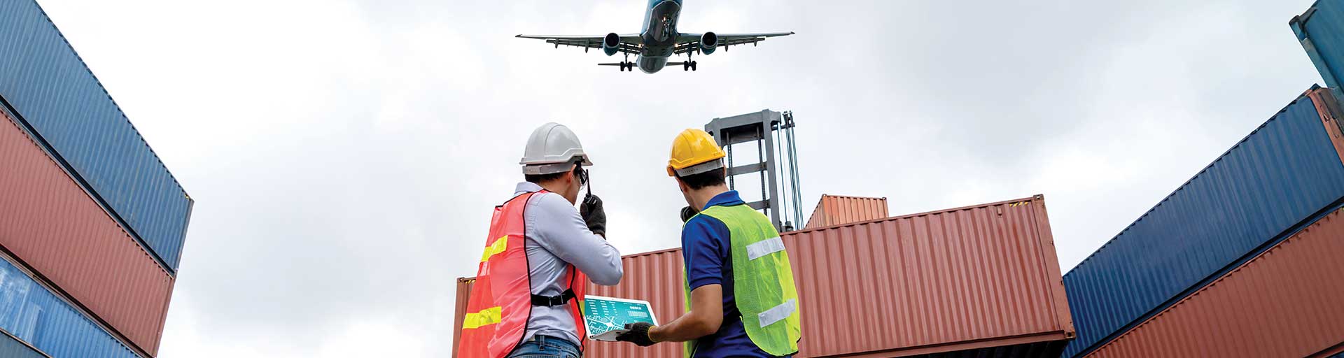 two people standing in front of cargo containers