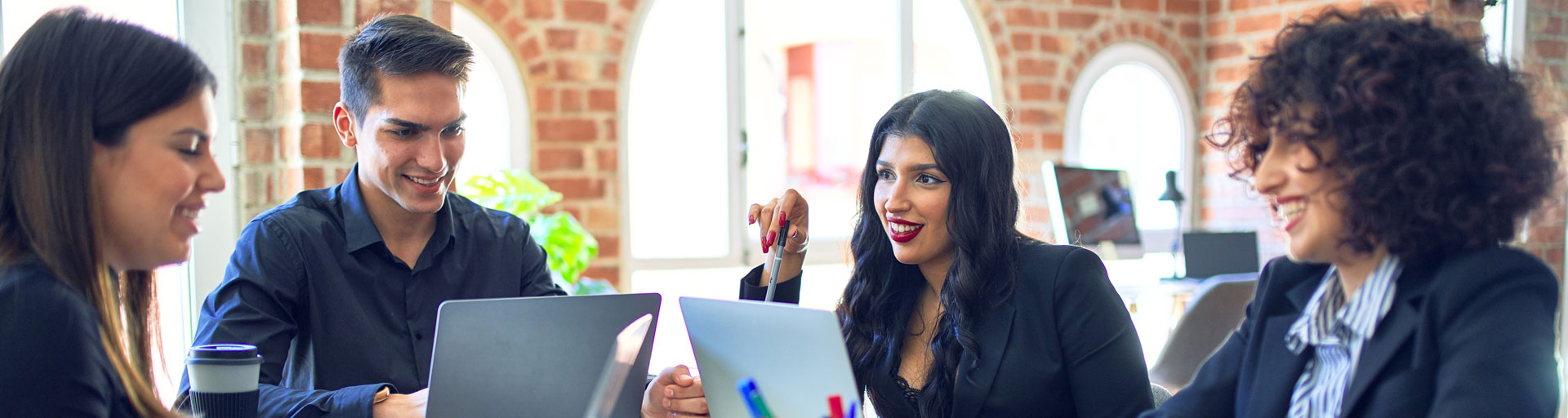 smiling people working together on a project using laptops