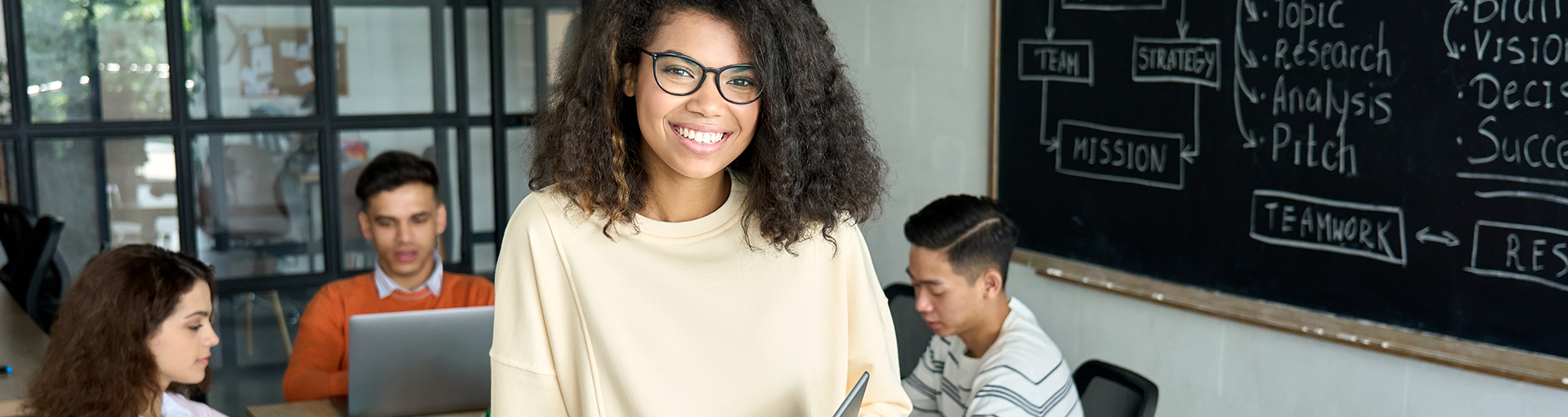 smiling student sitting on a table in a classroom