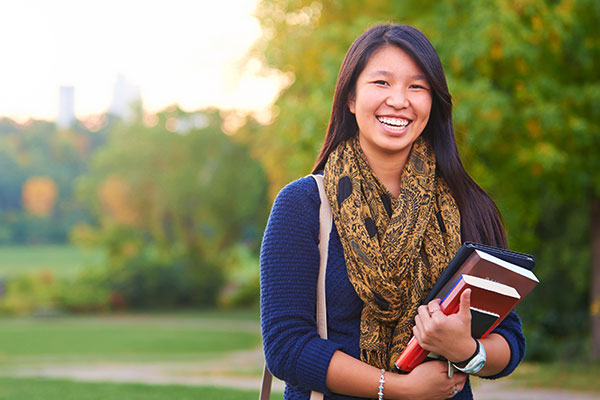 female student smiling carrying books