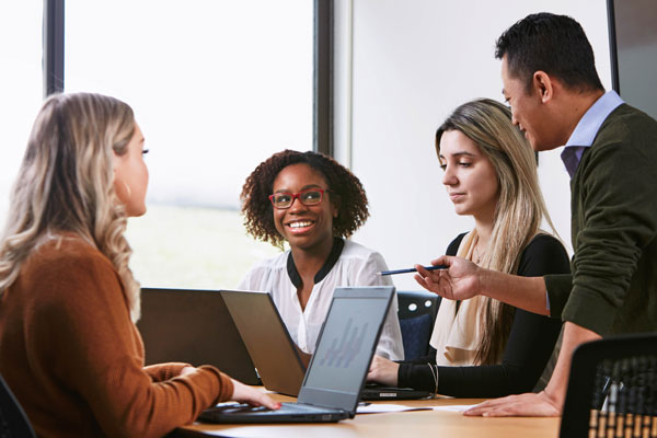 student smiling at mentor while sitting at table with two other people