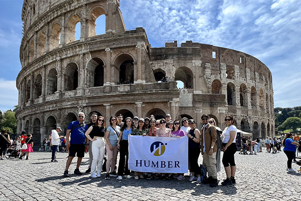 students holding a humber banner in front of a building