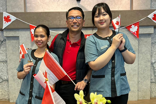 three people smiling and holding Canadian flags