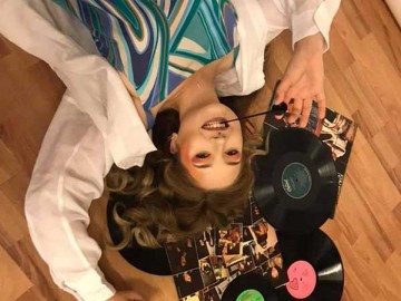 female model posing on the floor with records