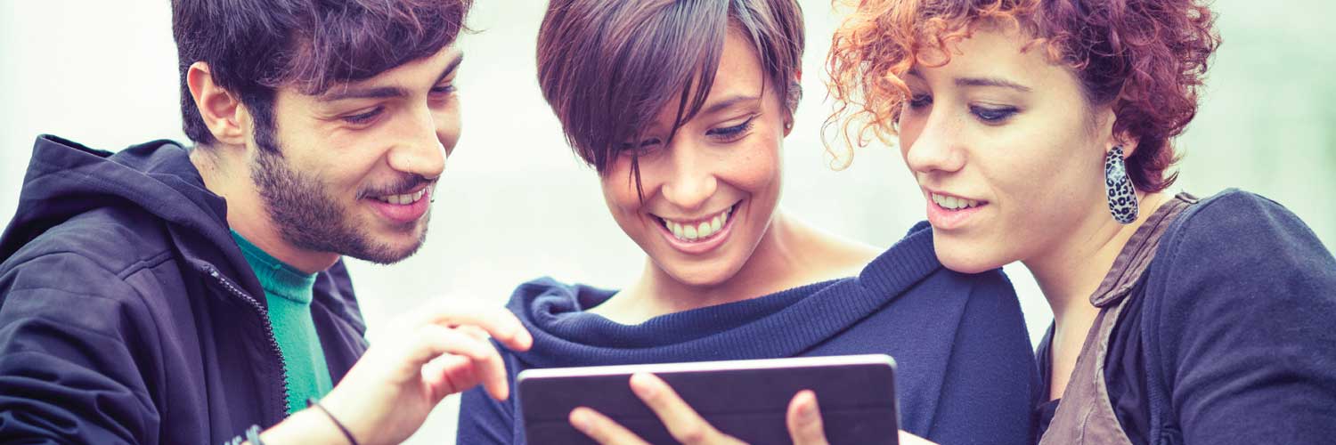 Three smiling students using an ipad
