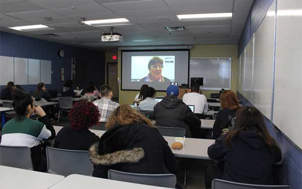 classroom of students listening to a video call in