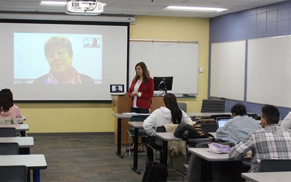 classroom of students listening to a video call in