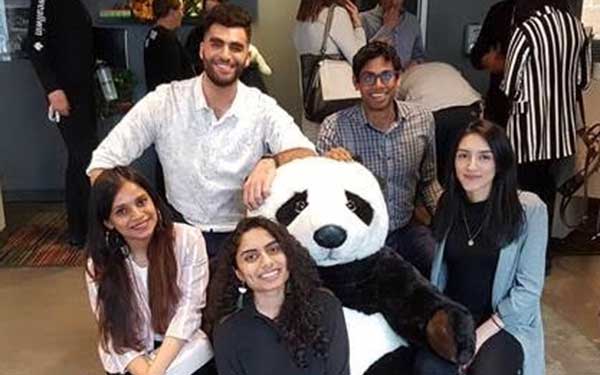 four students pose with a stuffed panda