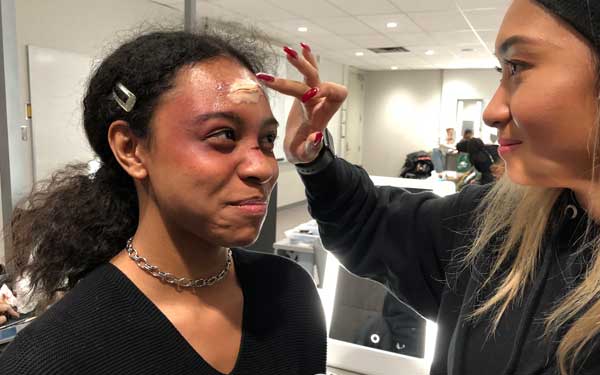 Woman having zombie makeup applied to her